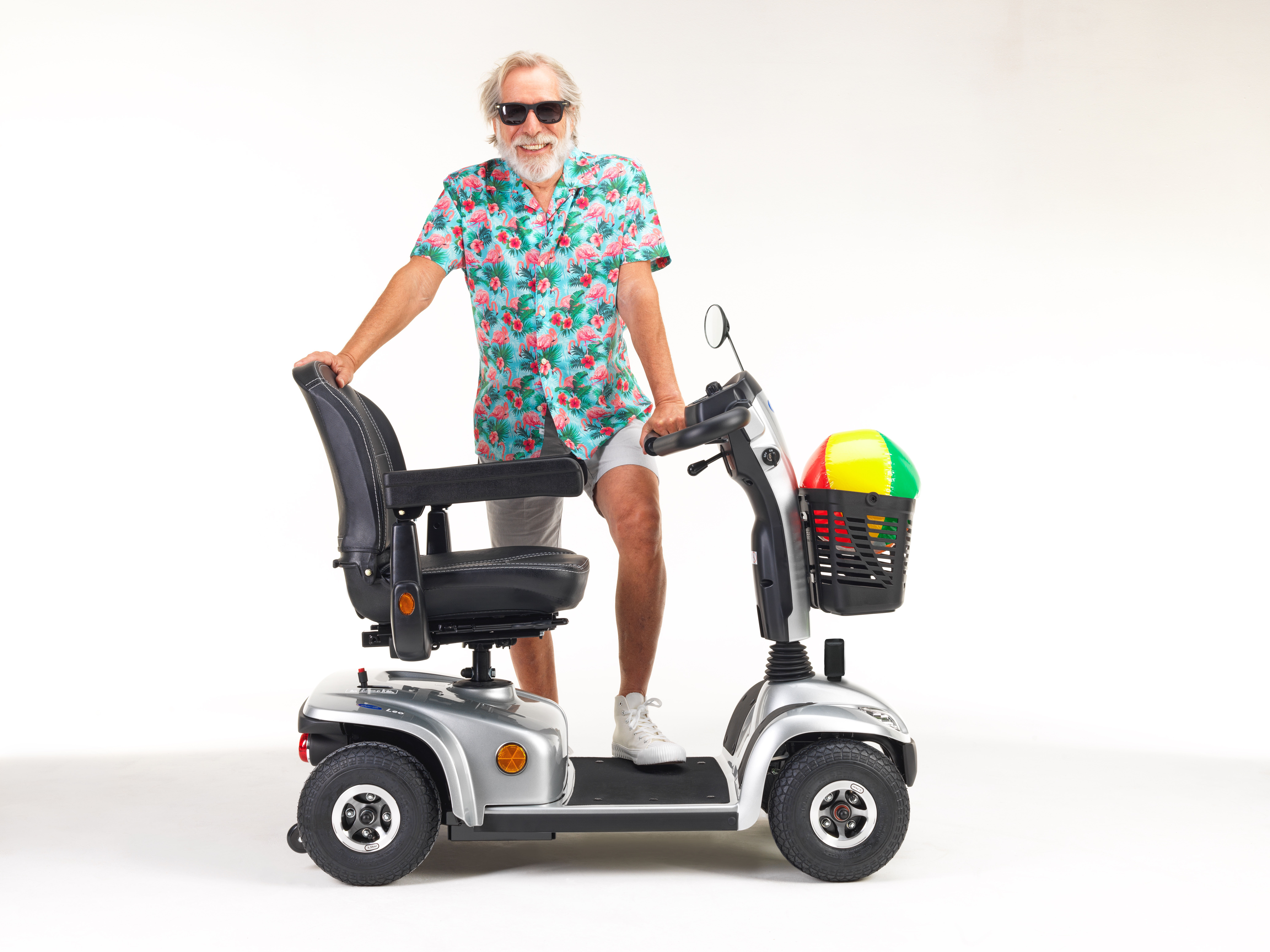 älterer Mann mit buntem Hand neben einem Elektromobil